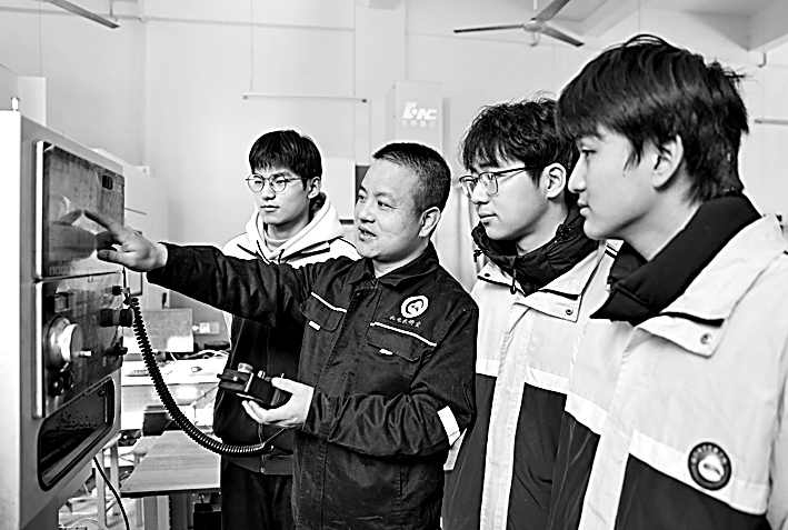 江西省瑞昌中等专业学校3D打印班,老师给学生讲解工业机器人的基本操作流程。魏东升摄/光明图片