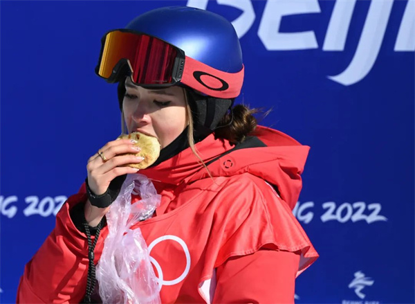 2月14日，北京2022年冬奥会自由式滑雪女子坡面障碍技巧资格赛在张家口云顶滑雪公园举行。图为谷爱凌在比赛后吃韭菜盒子。中新社记者 翟羽佳 摄