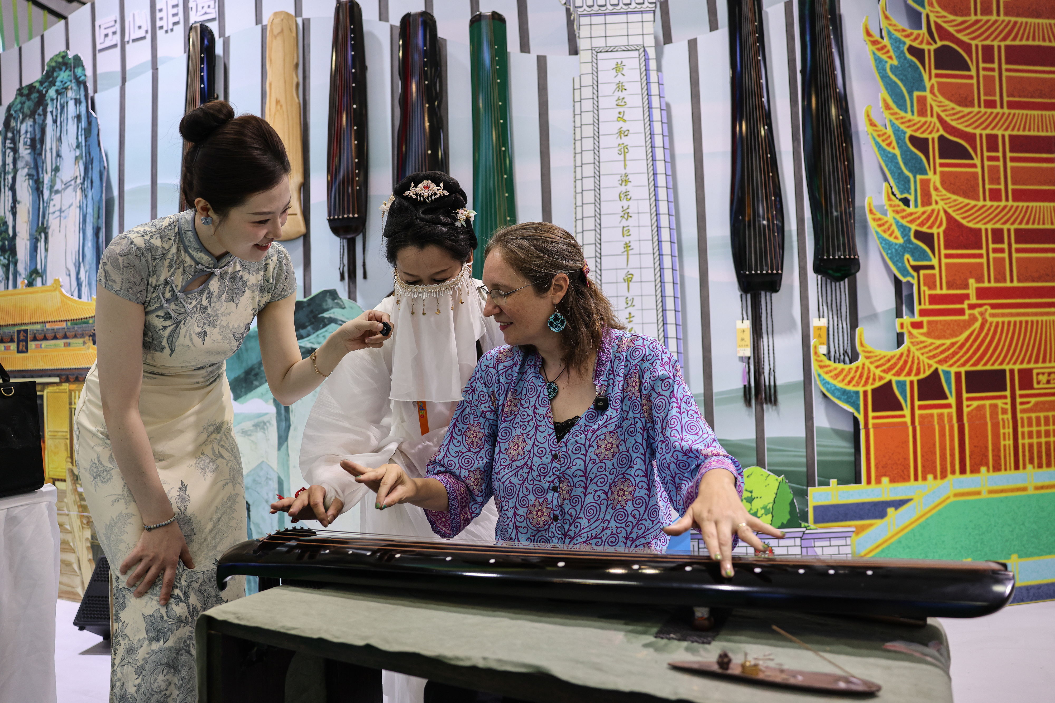 2026年4月15日，海南海口，第六届消博会国货精品展区外国参观者体验中国古琴。